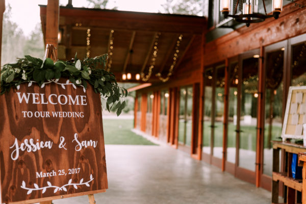 Rustic welcome sign at wedding with a eucalyptus topper